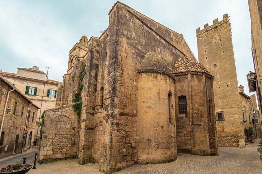 Un bâtiment historique en pierre, doté d’une tour, situé sur une rue pavée et présentant une architecture traditionnelle. 3