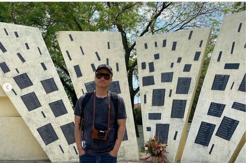 En person står foran et monument med inskriptioner. 1