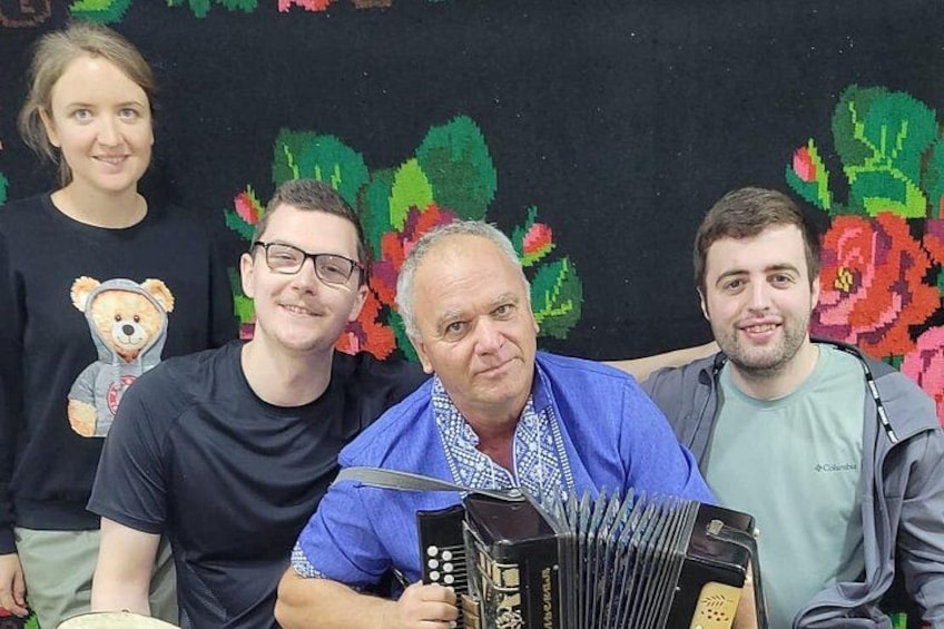 Fire personer, hvoraf én holder en harmonika. 3