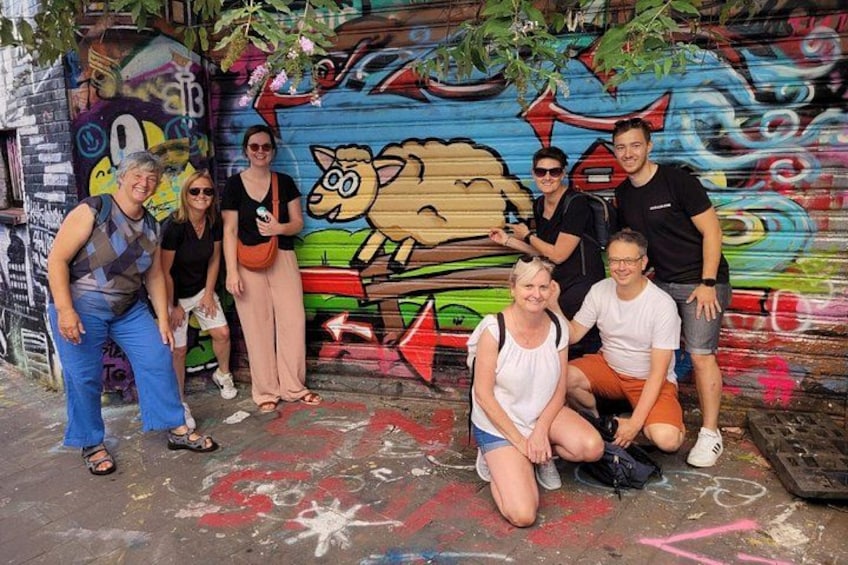 A group of people posing in front of a colorful graffiti wall. 3