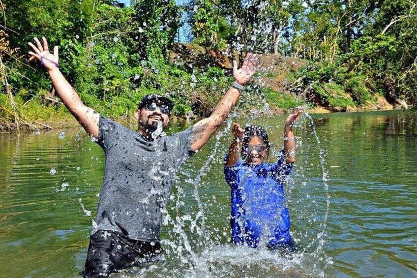 A person splashing water in a river surrounded by greenery. 2