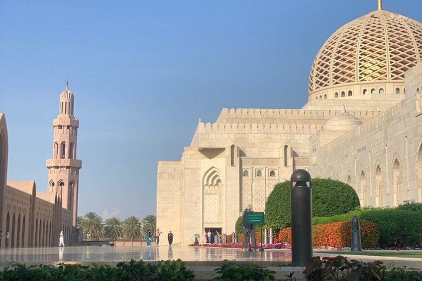 A large mosque with a prominent dome and minaret, surrounded by a well-maintained garden and a reflective water feature. 2