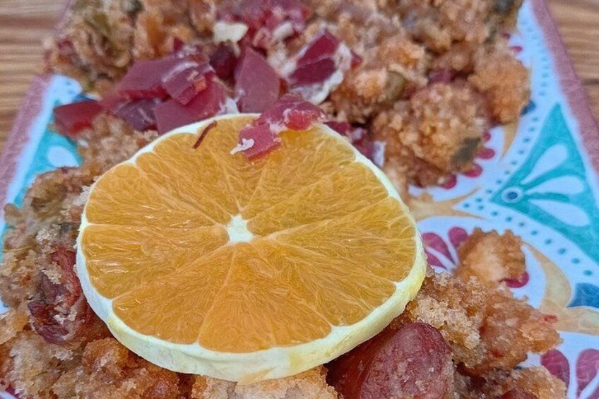 Un plato con comida frita, una rebanada de naranja y trozos rojos. 4