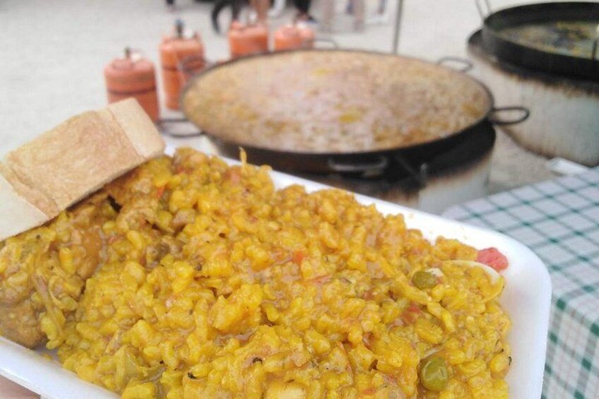 Un plato de curry amarillo con pan, una fuente de comida al fondo y un mantel a cuadros. 3