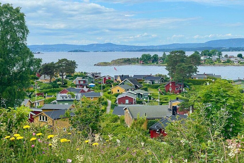 Ein Küstendorf mit Häusern, einem Gewässer und Bergen im Hintergrund. 1