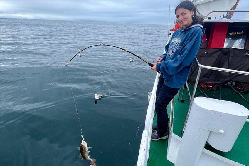 En person fisker fra en båd, med en fisk på snøren. 4