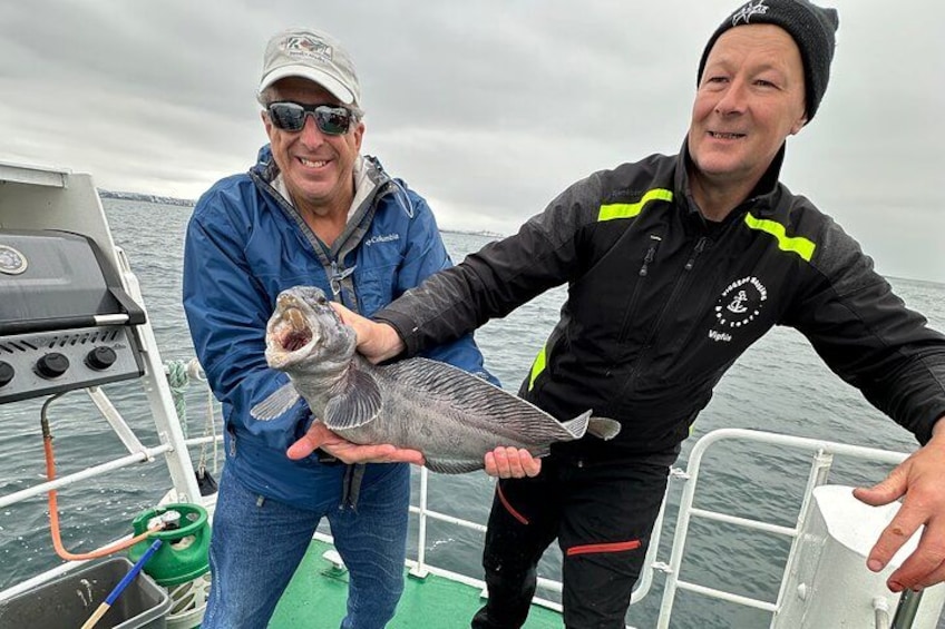 Due persone su una barca che tengono in mano un pesce. 3