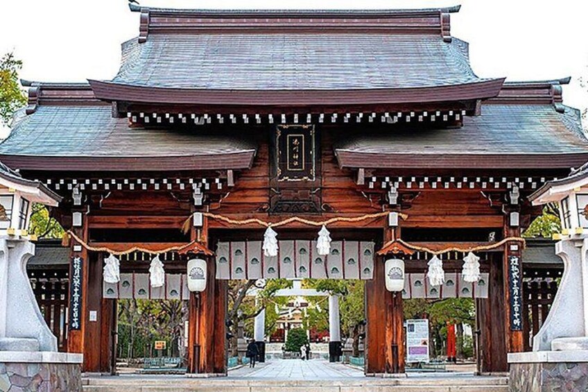 A traditional Japanese gate with wooden pillars and a tiled roof. 5