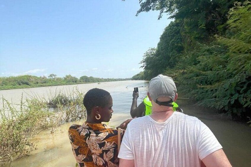 Two people standing by a river, one holding a camera. 2
