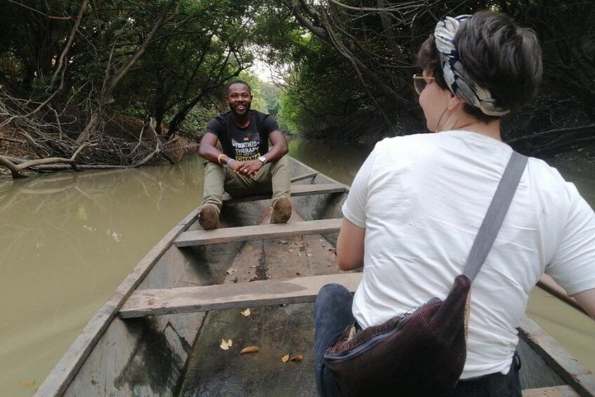 Two people in a wooden boat on a river surrounded by dense trees. 3
