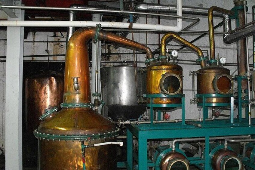 Equipo de destilación industrial con componentes de cobre y estructuras metálicas verdes. 3