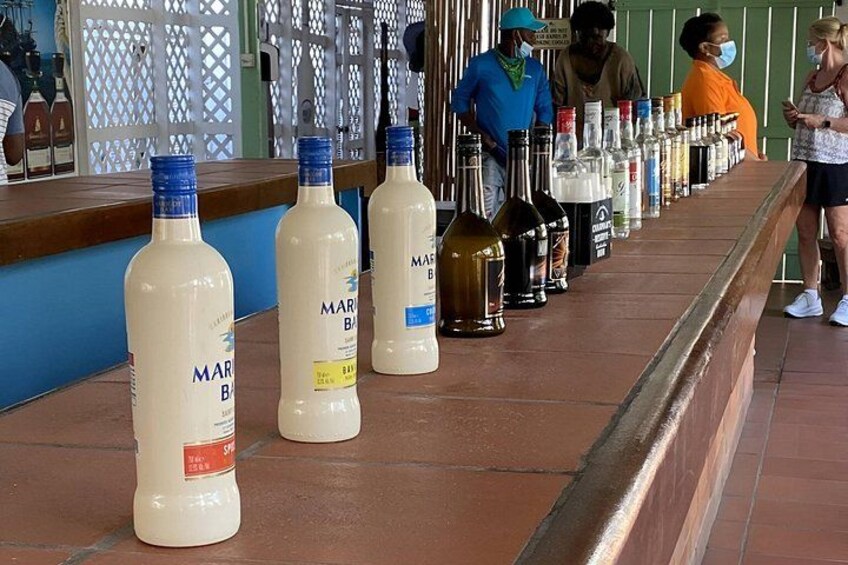 Una barra con una fila de botellas, incluyendo 'MARS B' y 'MARS B' con etiqueta amarilla, y una persona con una camisa anaranjada. 2