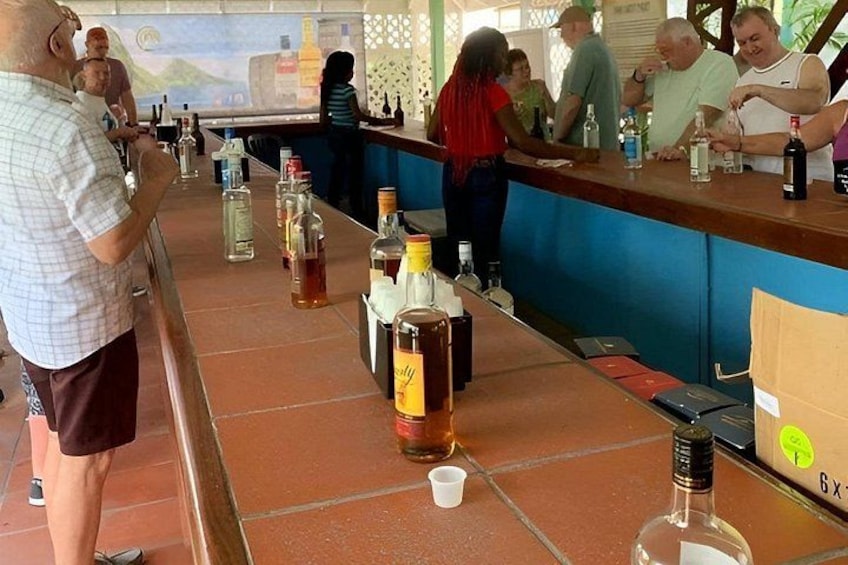 Un bar con piso de baldosas, botellas de alcohol y una barra donde hay gente de pie. 1