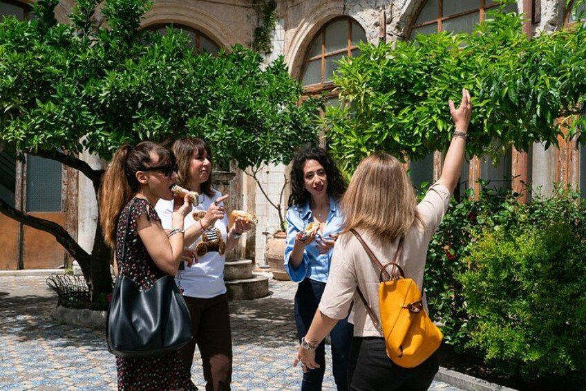A group of people walking in a courtyard with trees and a building in the background. 2