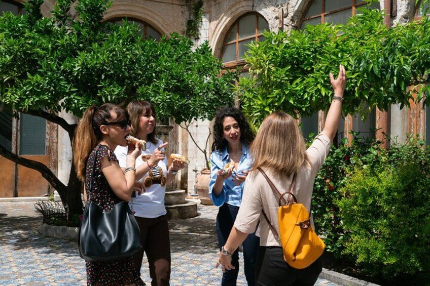 A group of people walking in a courtyard with trees and a building in the background. 3