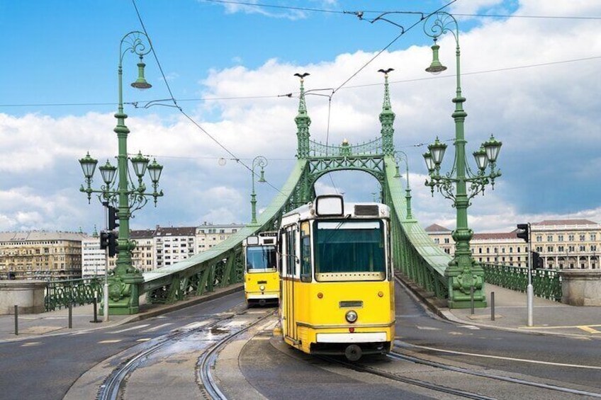 Un tranvía amarillo sobre un puente verde con farolas decorativas. 3