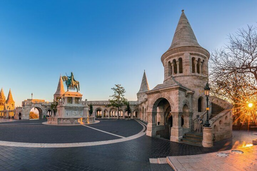 Una plaza histórica con un monumento central, un edificio grande de techo cónico y una zona pavimentada circular. 2