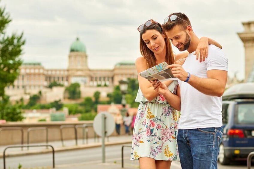 Una pareja posa frente a un edificio histórico con una cúpula, sosteniendo un mapa. 4