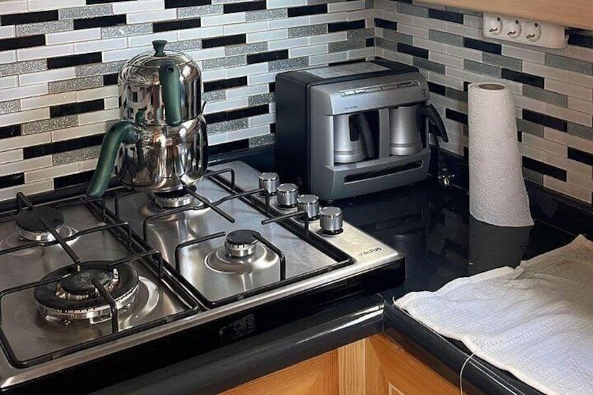A kitchen with a gas stove, a coffee maker, and a microwave. 3
