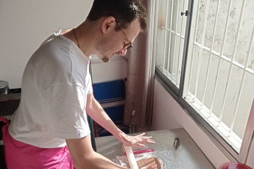 En person i hvid skjorte og pink nederdel arbejder ved et vindue med metalgitter, måske rengør eller inspicerer vinduet. 4
