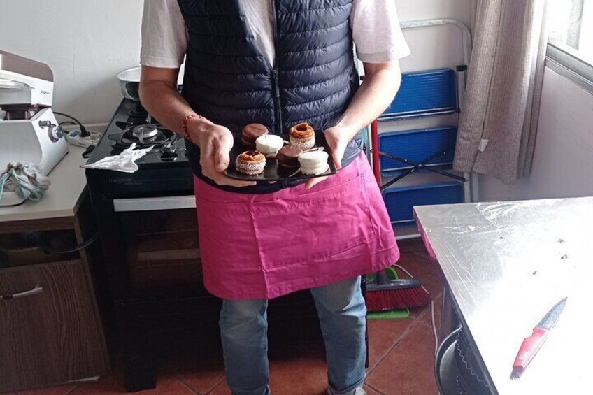 En person holder en bakke med kager i et køkken. 3
