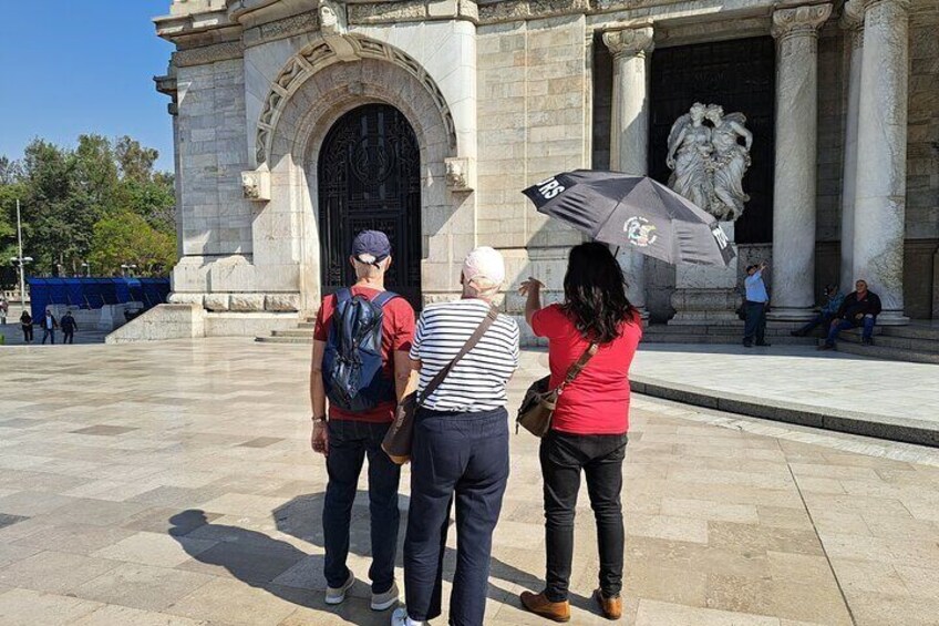 Un grupo de personas de pie frente a un arco de piedra grande con una estatua en su interior. 3