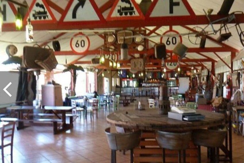 Un restaurant à la décoration d’époque, avec une grande table ronde, des chaises en bois et un plafond orné de panneaux de signalisation et de chiffres. 5
