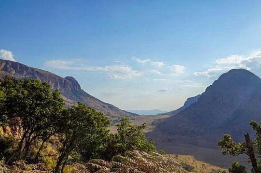 Un paysage montagneux avec une vallée et une végétation clairsemée. 1