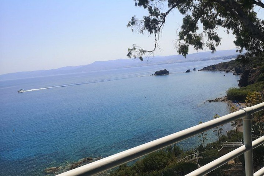 A coastal view with a boat on the water, a rocky shoreline, and a clear sky. 4
