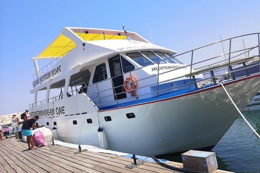 A boat named 'Mediterranean One' docked at a pier with people around it. 3