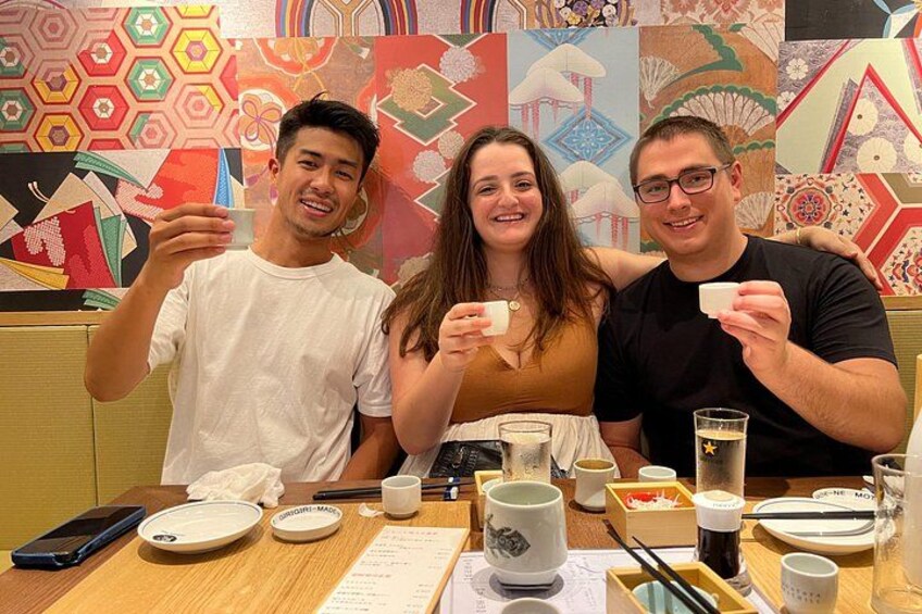 Three people sitting at a table with cups, a smartphone, and a menu. 3