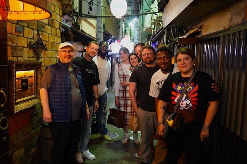 A group of people standing in a narrow alleyway with brick walls and a street lamp. 4