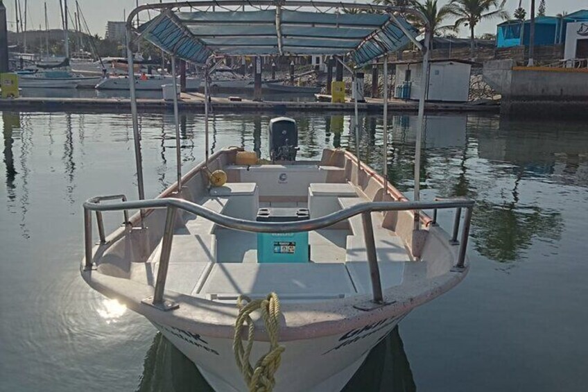 A boat docked at a marina with a covered area and other boats in the background. 2