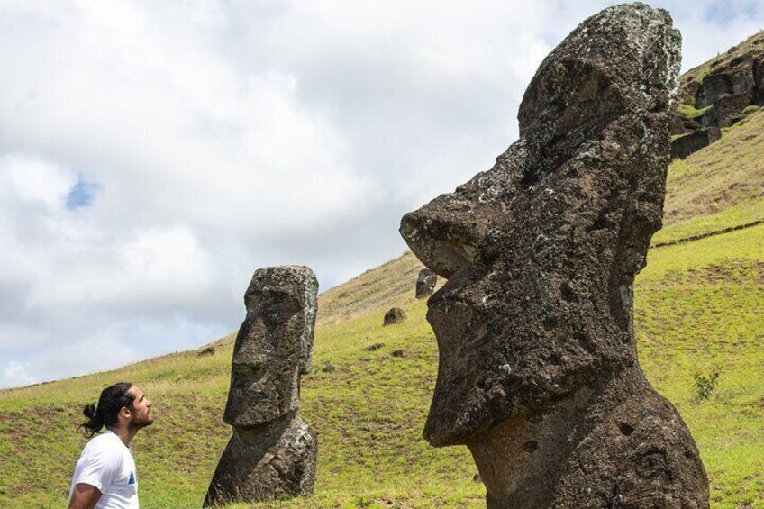 Two Moai statues on a grassy hill with a cloudy sky. 4