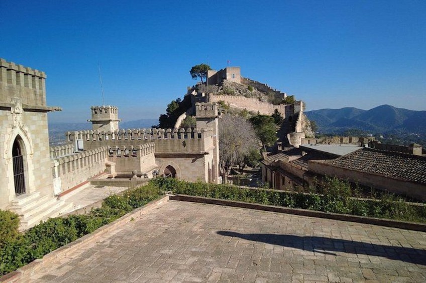 A historic fortress with stone walls and towers, a paved courtyard, and a mountainous backdrop. 4