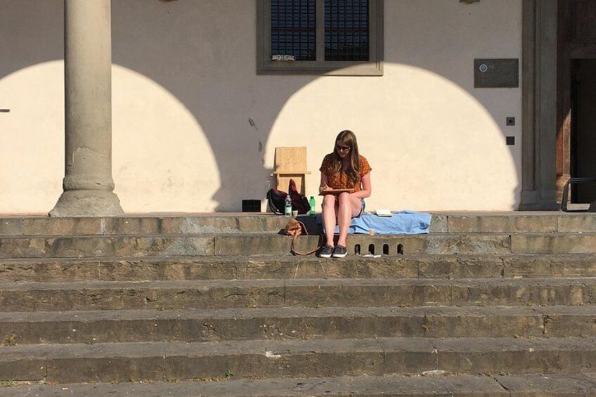 A person sitting on steps with a building in the background. 3