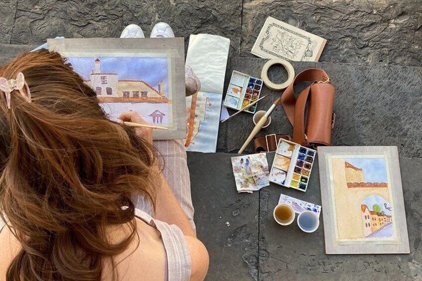 A person painting a landscape on a canvas, with art supplies and a sketch nearby. 5