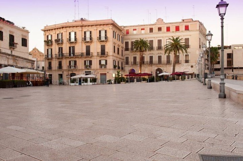 A paved square with buildings, a street lamp, and palm trees. 4