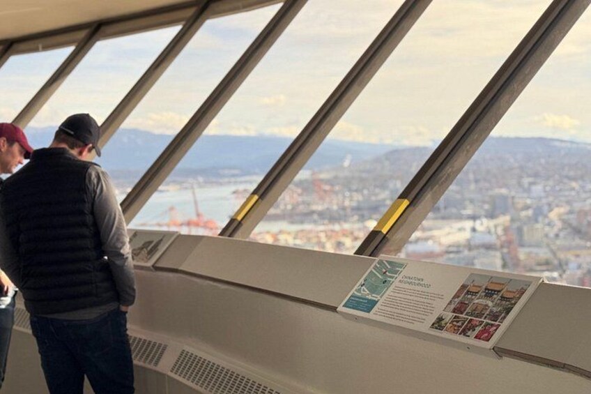 A person standing inside a building with a view of a cityscape through large windows. 1