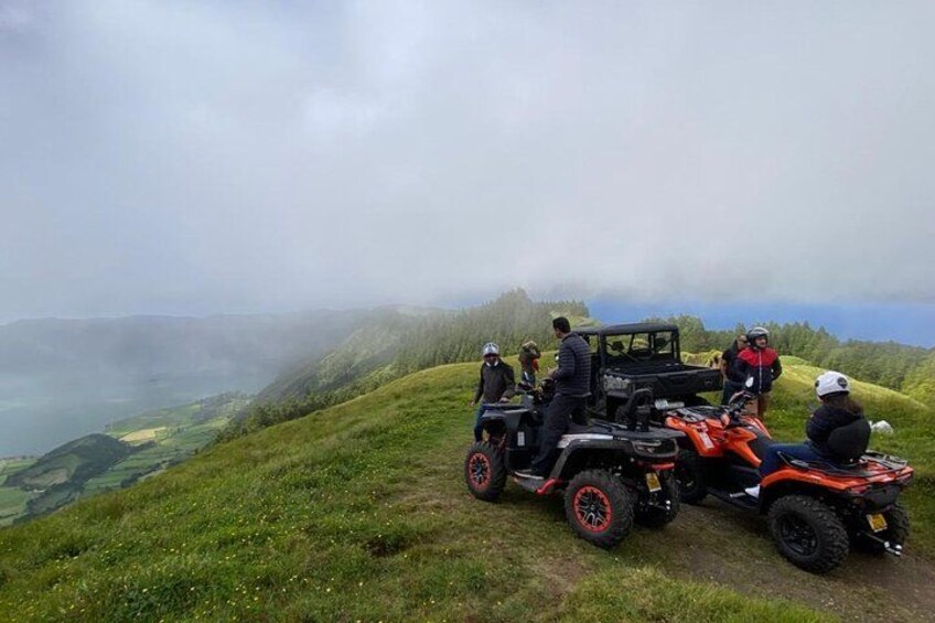 Un groupe de personnes se trouve sur une colline, à proximité de véhicules tout-terrain. 3