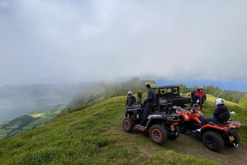 A group of people on a hill with a jeep and an ATV. 2