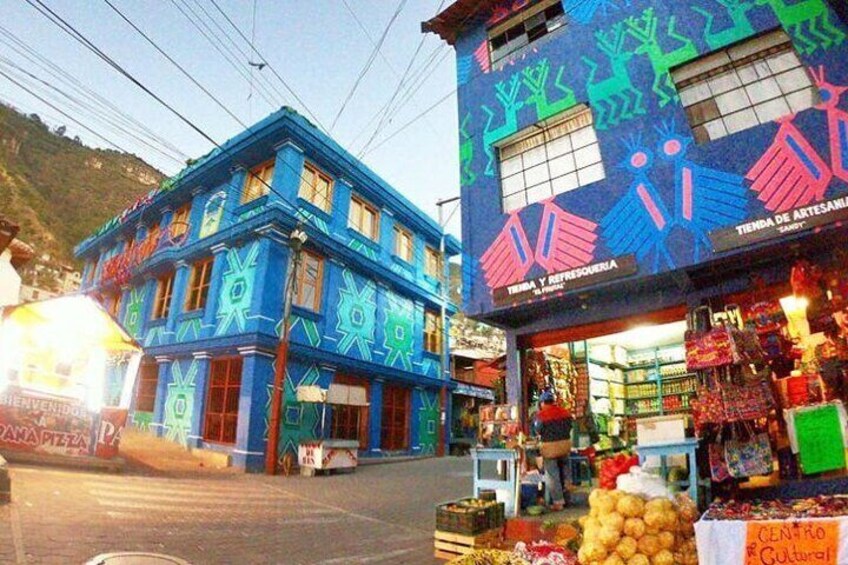 A colorful building with a blue facade and a shop with various items displayed outside. 1