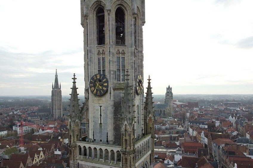 A tall clock tower with a clock face, surrounded by a cityscape with various buildings. 2