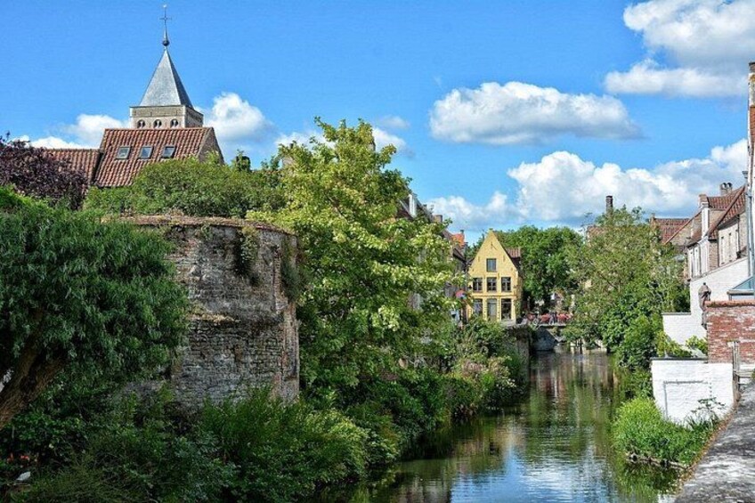 A canal with buildings, a church, and greenery. 3