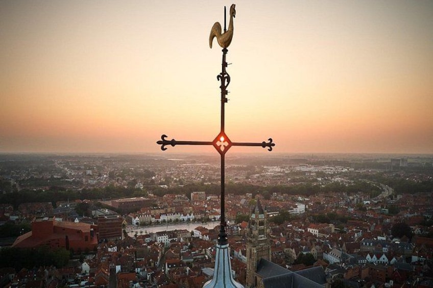 A weather vane atop a building with a cityscape in the background. 1