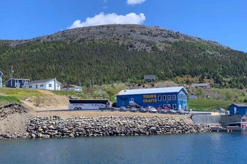 A lakeside town with a blue building labeled "TOURS CRAFTS," a stone pier, and a mountain in the background. 4