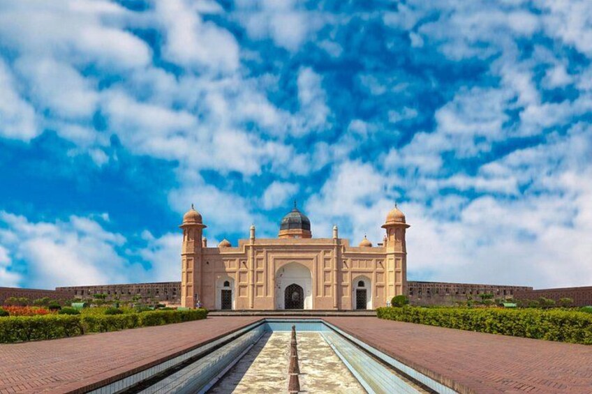 A large, historic building with a central dome and two towers, surrounded by a paved area and a water feature. 3