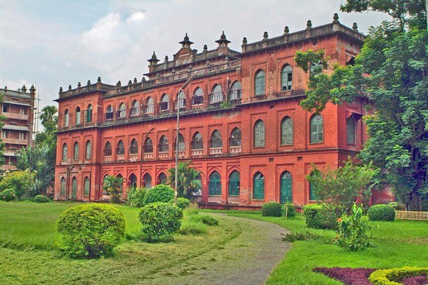 A large red building with arched windows and a garden in front. 4