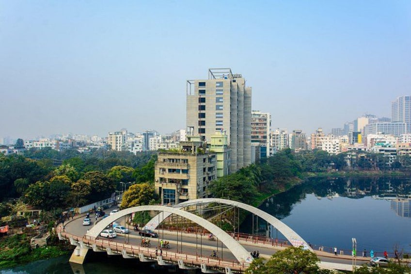 A cityscape with a prominent modern building, a curved bridge, and a calm river. 1