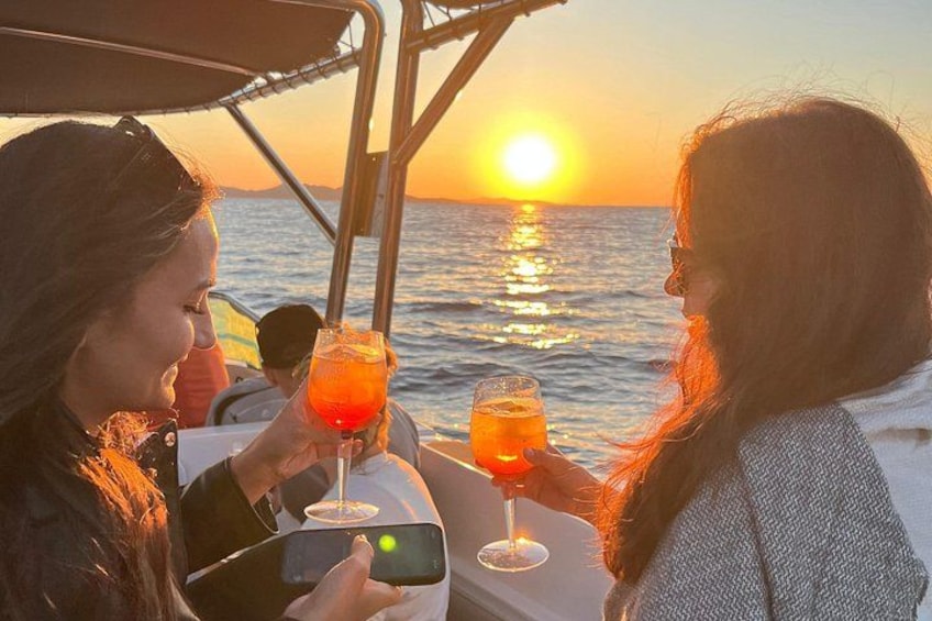 Zwei Personen stoßen auf einem Boot bei Sonnenuntergang mit Getränken an. 3